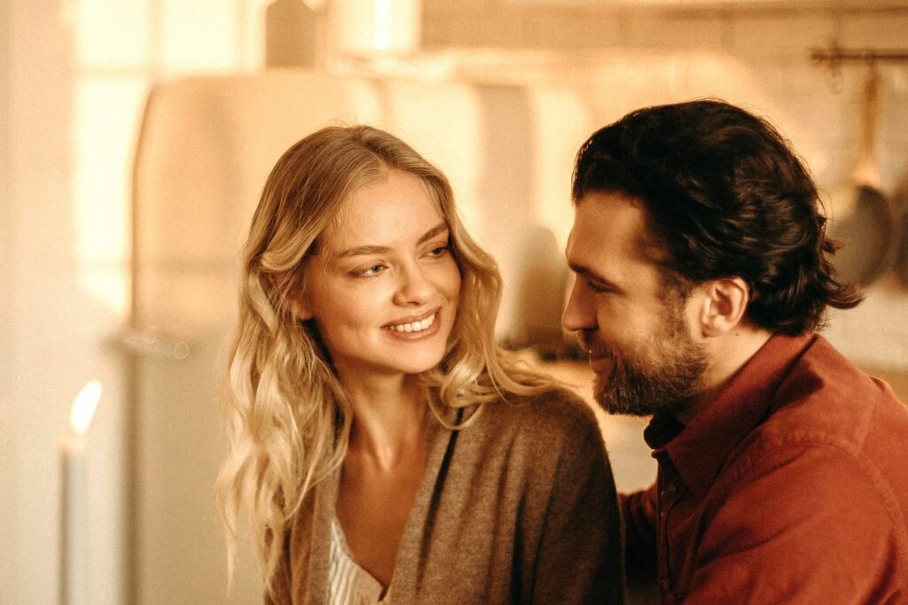 Pareja sonriendo y mirándose con complicidad, reflejando confianza y conexión emocional a través de una sonrisa saludable
